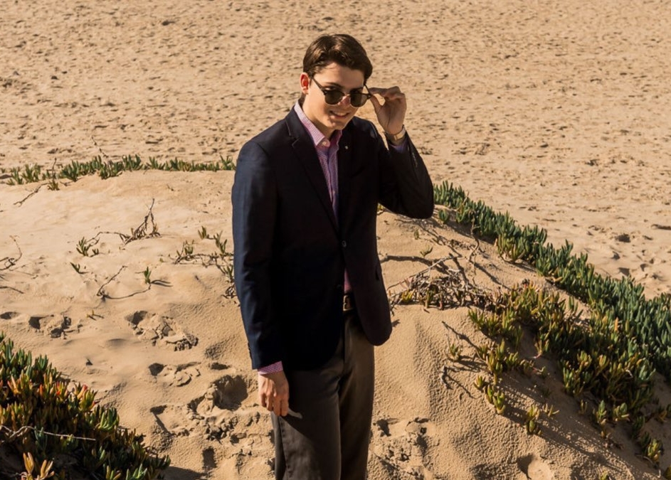 Photo of me wearing a suit and sunglasses at the beach.